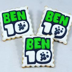 three decorated cookies with the words ben 10 and paw prints on them, sitting next to each other