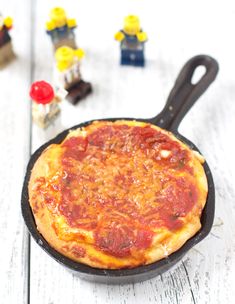 a pizza sitting in a pan on top of a white table next to legos