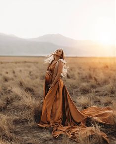 a pregnant woman standing in the middle of a field