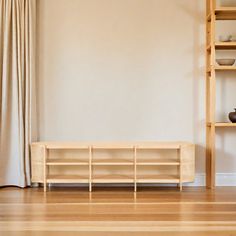 a living room with wooden floors and shelves on either side of the window sill