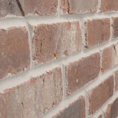 a brick wall that has been made from red and white bricks with some light brown paint on it