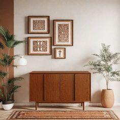 a living room with pictures on the wall and plants in vases next to it