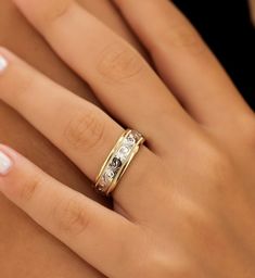 a woman's hand wearing a gold ring with two diamonds on the middle finger