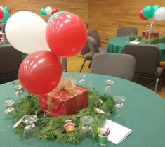 red and white balloons are on top of a present box in the center of a table