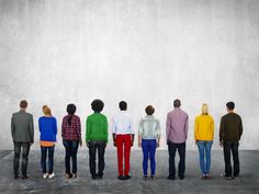 five people standing in front of a wall with one person looking at the other side