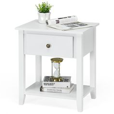 a white nightstand table with magazines and a potted plant