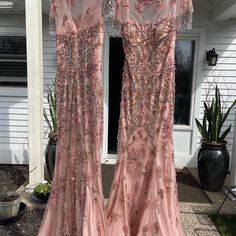 two pink dresses hanging on the side of a house