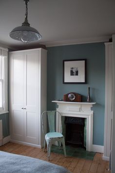 a bedroom with blue walls, white furniture and a fire place in the fireplace area