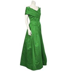 For Sale on 1stDibs - Dramatic 1980's emerald green satin gown by Arnold Scaasi. The dress has a pleated off the shoulder detail that wraps around the front bust. The asymmetrical Green Pre-draped Satin Gown, Green Satin Gown With Pleated Bodice, Green Evening Dress With Pleated Bodice, Green Evening Dress With Pleated Bodice For Gala, Green Pleated Bodice Evening Dress For Gala, Green Pre-draped Evening Gown, Green Gala Gown With Pleated Bodice, Green Cocktail Evening Dress With Pleated Bodice, Green Pleated Bodice Evening Dress For Cocktail