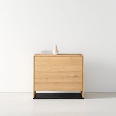 a white vase sitting on top of a wooden dresser