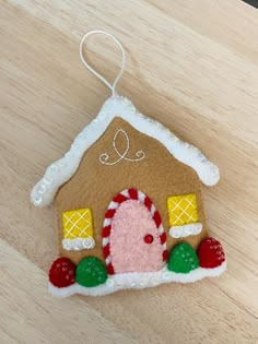 a gingerbread house ornament hanging on a wooden table