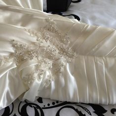 a white wedding dress with beaded details on the waistline and back, laying on a bed