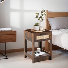 a small wooden table with a potted plant sitting on it next to a bed