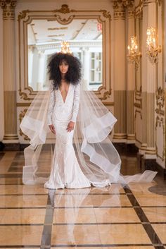 a woman in a white wedding dress standing on a marble floor with her veil draped over her head