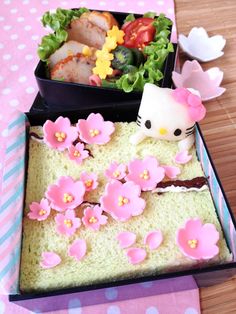 a hello kitty bento box with rice and flowers on the inside is filled with food