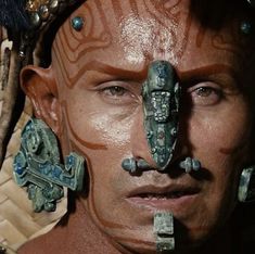 a close up of a person with face paint and decorations on his head, looking at the camera