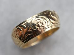 a gold wedding ring with skulls and bones on the inside is sitting on a gray surface