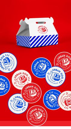 a red table topped with lots of blue and white stickers next to a box