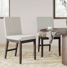 two white chairs sitting next to each other on top of a wooden dining room table