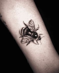 a black and white photo of a bee on the arm