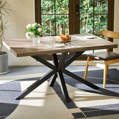 a wooden table sitting in front of a window on top of a carpeted floor