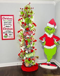 a christmas tree decorated with candy canes and an grino character standing next to it