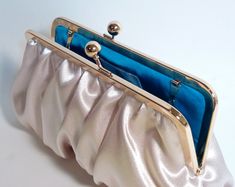 "Beautiful Champagne Satin clutch gathered at the top and bottom for an elegant, rich evening or bridesmaid bag. Perfect bridesmaid clutch for any time of year! Also comes in gold, ivory or your favorite color! Lining is your choice, just convo me what color you want! Fabric: Satin Lining: Satin Two layers of interlining and batting Gold kisslock frame Top Width 8\" Bottom Width 9\" Height 5 1/2\" Reinforced stitching for durability *Note: A chain can be added for $4.00. Please see my chain list Elegant Satin Finish Evening Bag, Elegant Satin Finish Evening Bag For Formal Events, Elegant Satin Finish Evening Bag For Formal Occasions, Elegant Satin Finish Evening Bag For Party, Elegant Evening Bag With Satin Lining For Wedding, Chic Satin Evening Bag For Wedding, Elegant Satin Clutch For Wedding, Bridesmaid Clutch, Bridesmaid Clutches