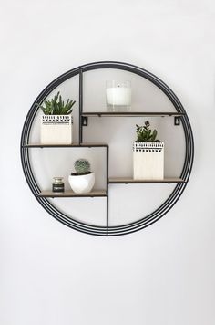 three shelves with plants and candles on them in front of a wall mounted circular mirror