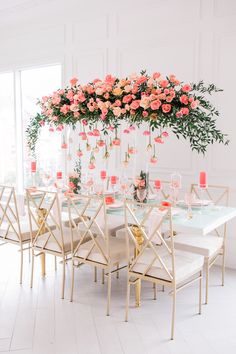 a dining room table with pink flowers hanging from the ceiling and candles on top of it