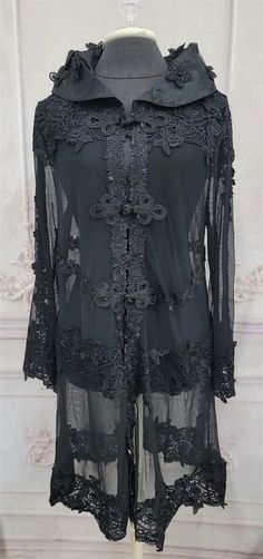 From the Victorian Trading Co: Silk Noir Floral Lace Duster Lightweight with a breezy, with a bit of stretch   this duster rests comfortably upon shoulders over a dress or blouse and makes an elegant cover-up. Front details with intricate frog lace buttons. Size L. Silk rayon spandex. Imported. Front to middle 12" (both sides)  Back underarm back 24" shoulder to hem 42 sleeve 25 Sheer Powered by SixBit's eCommerce Solution Black Lace Duster Outfit, Lace Duster Outfit, Duster Outfit, Goddess Wear, Duster Pattern, Lace Duster, Lace Button, Gothic Outfits, High Collar