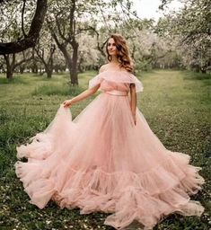 a woman wearing a pink dress standing in the grass with her hands on her hips