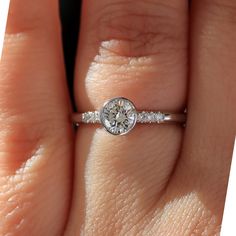 a woman's hand with a diamond ring on top of her finger and an engagement band