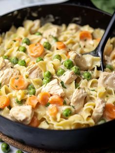 a skillet filled with pasta, peas and chicken