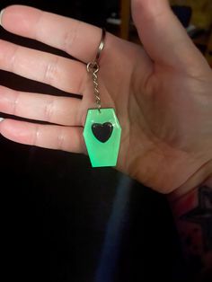 a hand holding a green heart shaped keychain