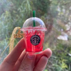 a hand holding up a starbucks drink in front of a window