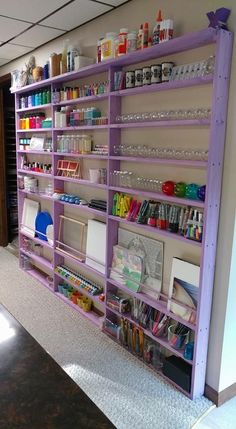 a purple shelf filled with lots of crafting supplies on top of a carpeted floor