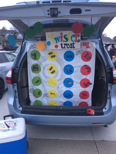 the back of a car with a bulletin board in it's trunk and several cars parked on the side of the road