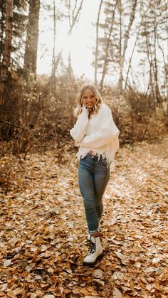 a woman is standing in the leaves talking on her cell phone