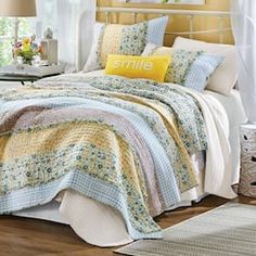 a bed with yellow and blue quilts on it