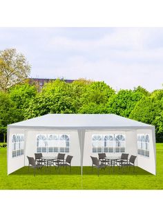 a white tent with tables and chairs under it in the middle of a grassy field