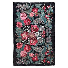 a black rug with red flowers and leaves on the front, along with an intricately designed border