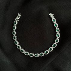 This elegant and stylish 925 sterling silver tennis bracelet is the perfect accessory to highlight your elegance and style. Adorned with emerald-colored CZ (Cubic Zirconia) oval cut stones, this bracelet features a beautiful waterway design. Suitable for everyday wear as well as special occasions and events, it will add a touch of sophistication to any outfit. With its high-quality craftsmanship and durable structure, this bracelet can be cherished for years to come. It also makes a wonderful gift for your loved ones.   Features: * Material : 925 Sterling Silver * Stone     : Emerald CZ (Cubic Zirconia) Oval Cut * Design   : Waterway Arrangement * Length   : Adjustable upon request. * Closure  : Secure Clasp System     Add a touch of elegance to your style with this bracelet! Elegant Silver Tennis Bracelet With Emeralds, Elegant Silver Emerald Tennis Bracelet, Bracelet Emerald, Silver Tennis Bracelet, Bracelet Tennis, Emerald Color, Tennis Bracelet, Cut Design, Oval Cut