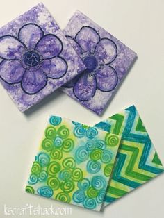 three square coasters with flowers painted on them