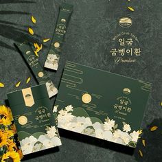 three packets with flowers on them sitting next to some yellow and white petals in front of a black background