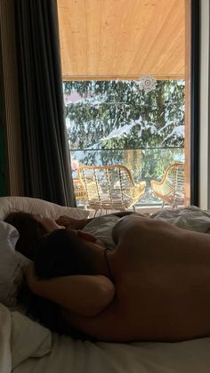 a naked man laying on top of a bed next to a window