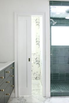 a bathroom with marble counter tops and green tiles on the walls, along with a walk in shower