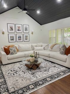 a living room with white couches and rugs in front of the windows, framed pictures on the wall