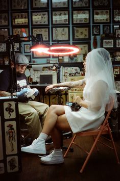 a bride and groom sitting in a chair at a barbershop with the lights on behind them