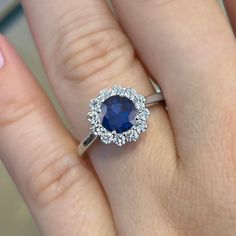 a woman's engagement ring with a blue sapphire and diamond halo around the band