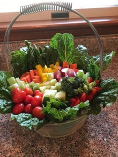 a basket filled with lots of vegetables on top of a counter next to a window